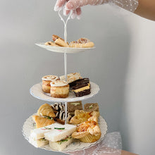 Load image into Gallery viewer, Three-tiered cake stand with assorted finger foods against a gray background