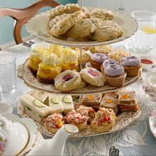 Load image into Gallery viewer, Three-tiered cake stand with assorted finger foods on a table setting.