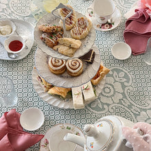 Load image into Gallery viewer, Tea party setup with pastries, teacups, and a teapot on a patterned tablecloth.
